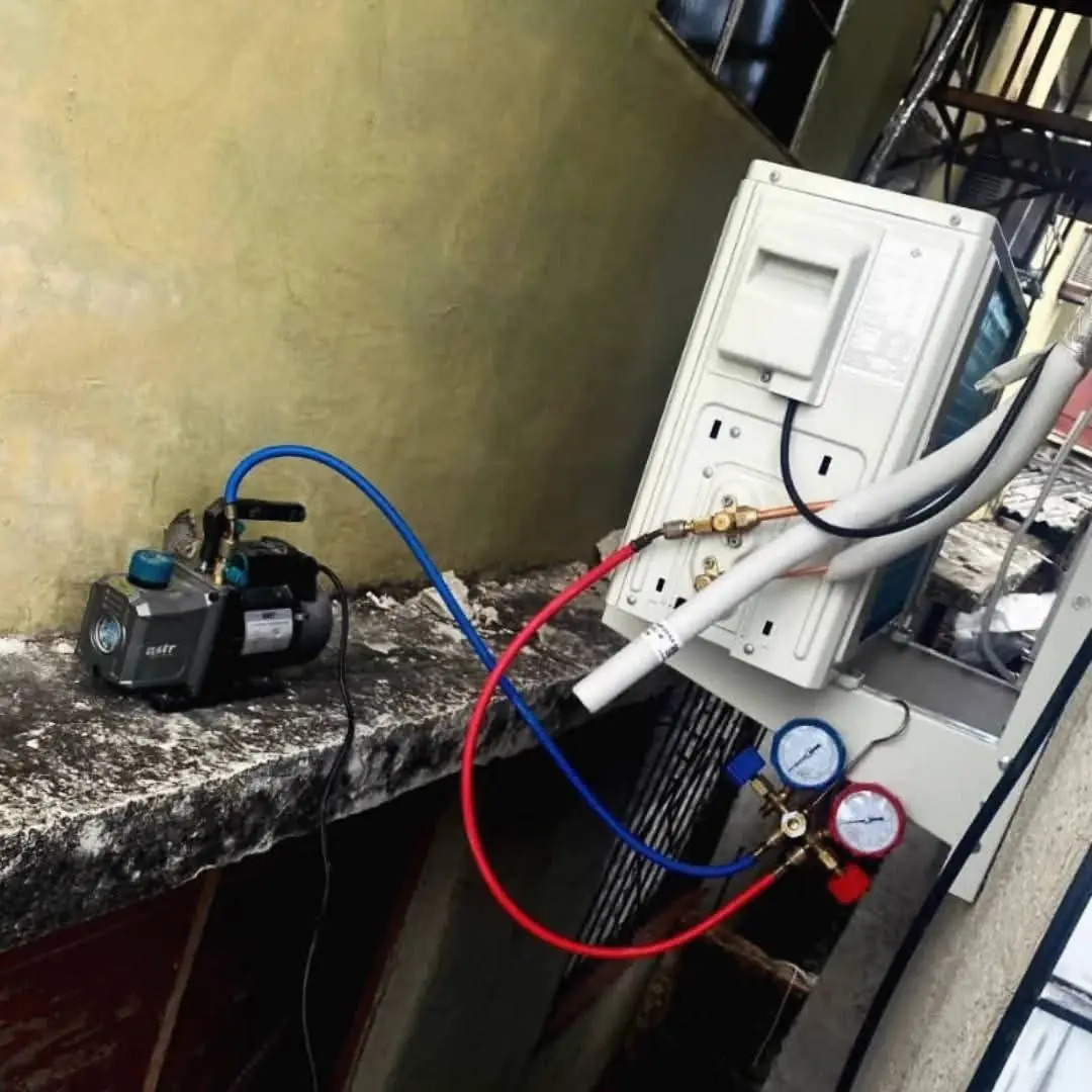 Bomba de vacío y manómetro conectados a la línea frigorífica durante una instalación