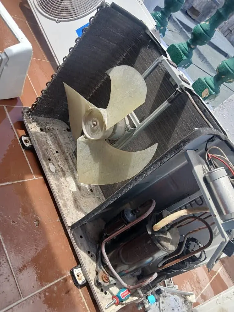 Unidad exterior abierta con el ventilador a la vista durante una reparación en Palma